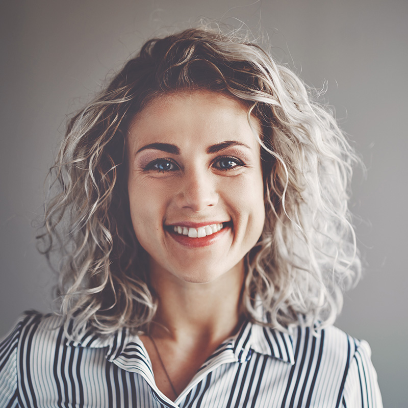 Smiling young business professional standing alone in an office